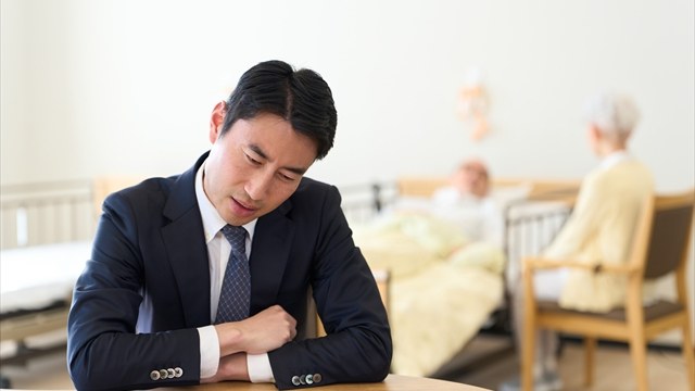 介護をしている親のそばで考えこむ人