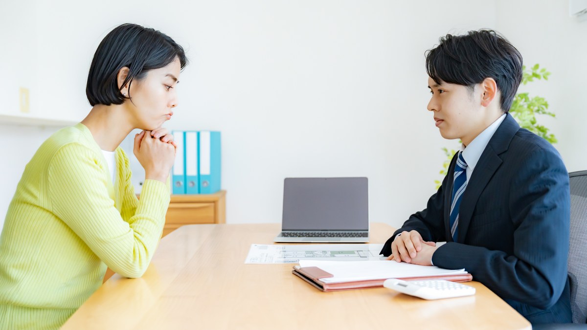 不動産会社の担当者と向かい合って話を聞いている